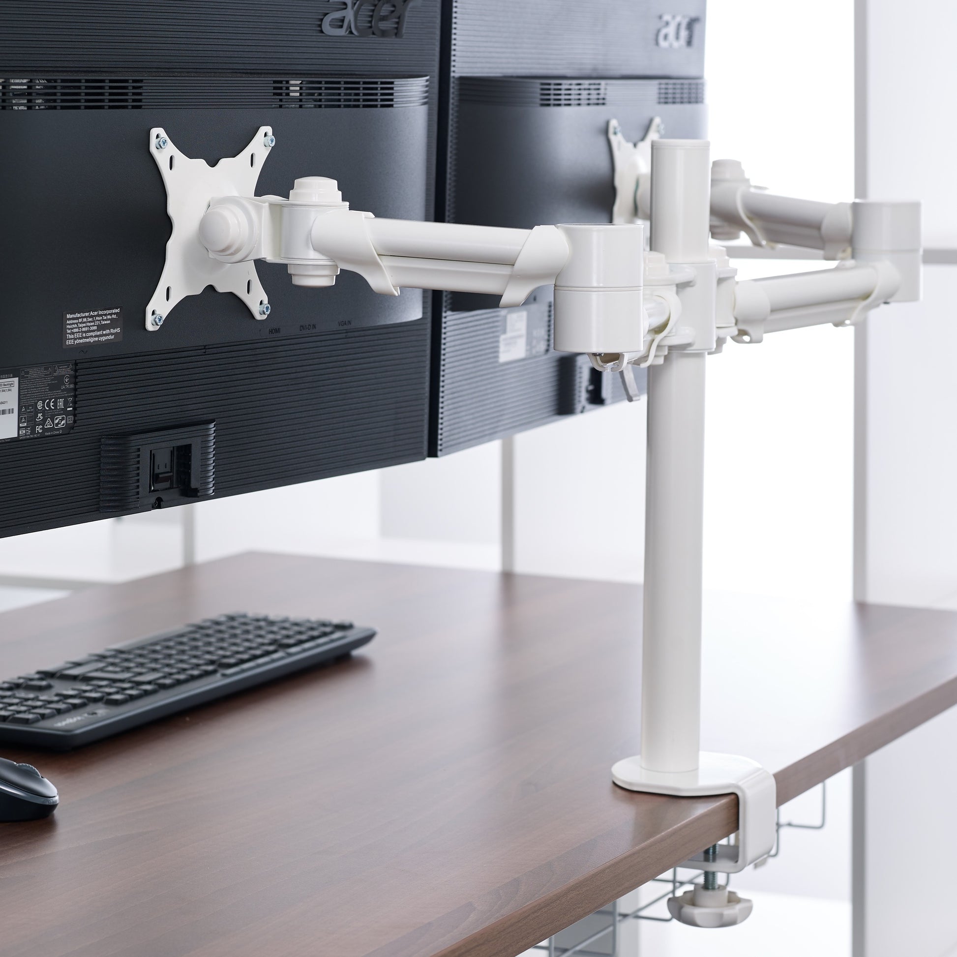 White twin monitor arms holding computer screens on desk