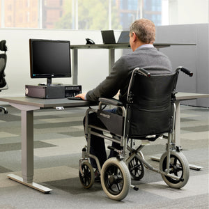 Man in wheelchair using heavy duty adjustable desk.